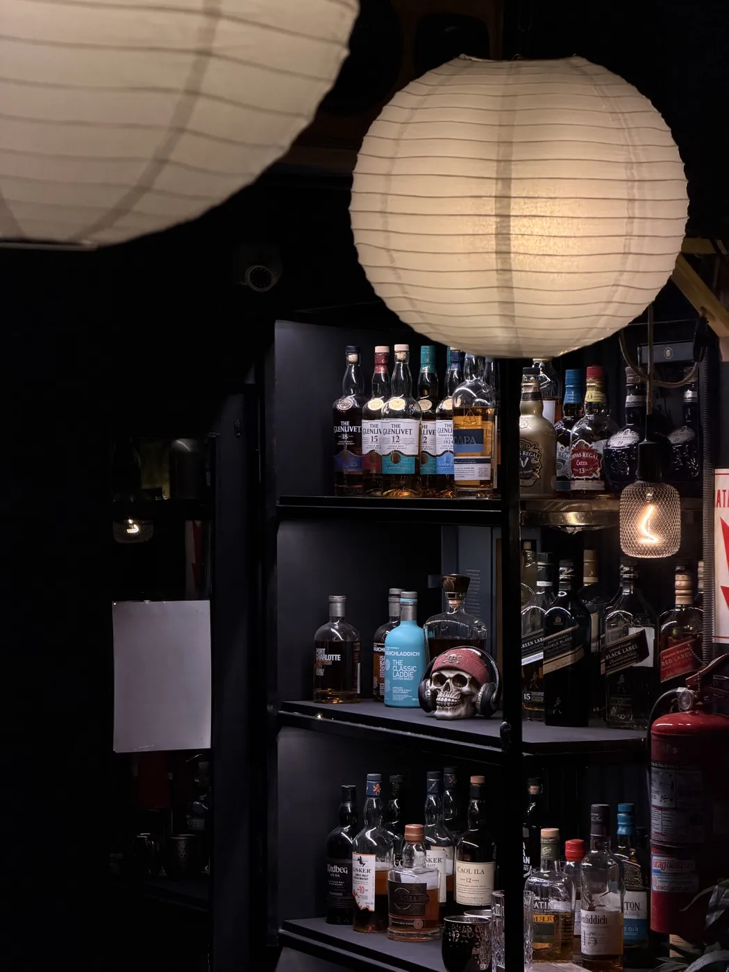 Estantes de bebidas iluminados bajo un farol en Casa Manuel