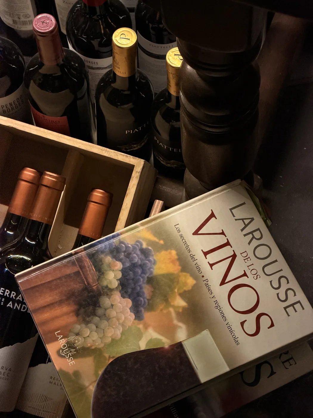 Vinos en caja de madera junto a un libro de vinos